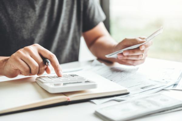 man's hands typing on calculator